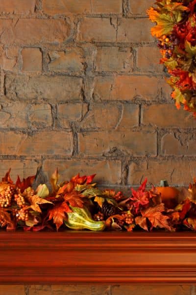 Indoor fireplace in Madison with brick surround and mantel decorated with autumn leaves and pumpkins
