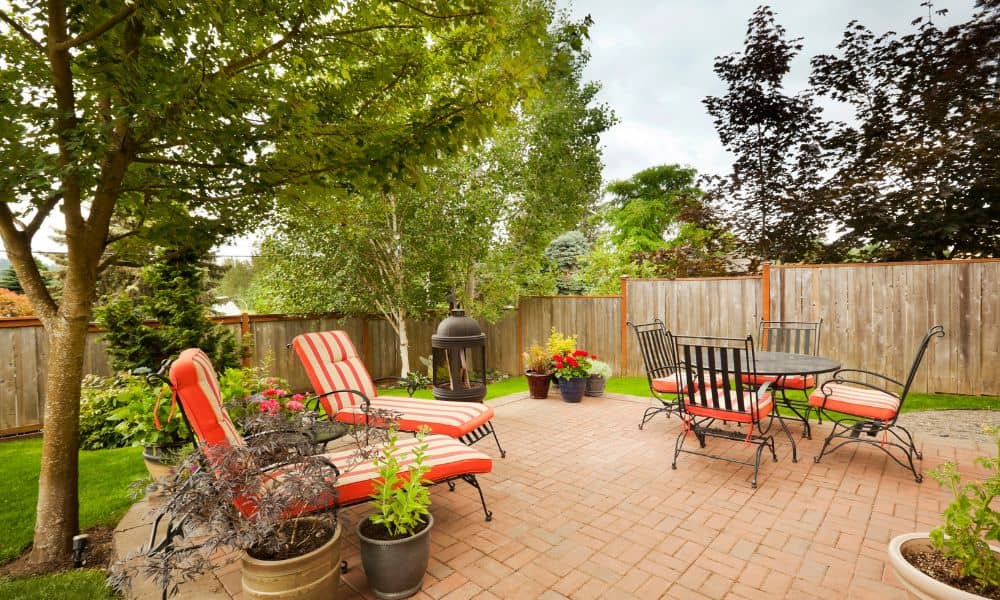 Backyard patio built with brick pavers featuring outdoor furniture and plants