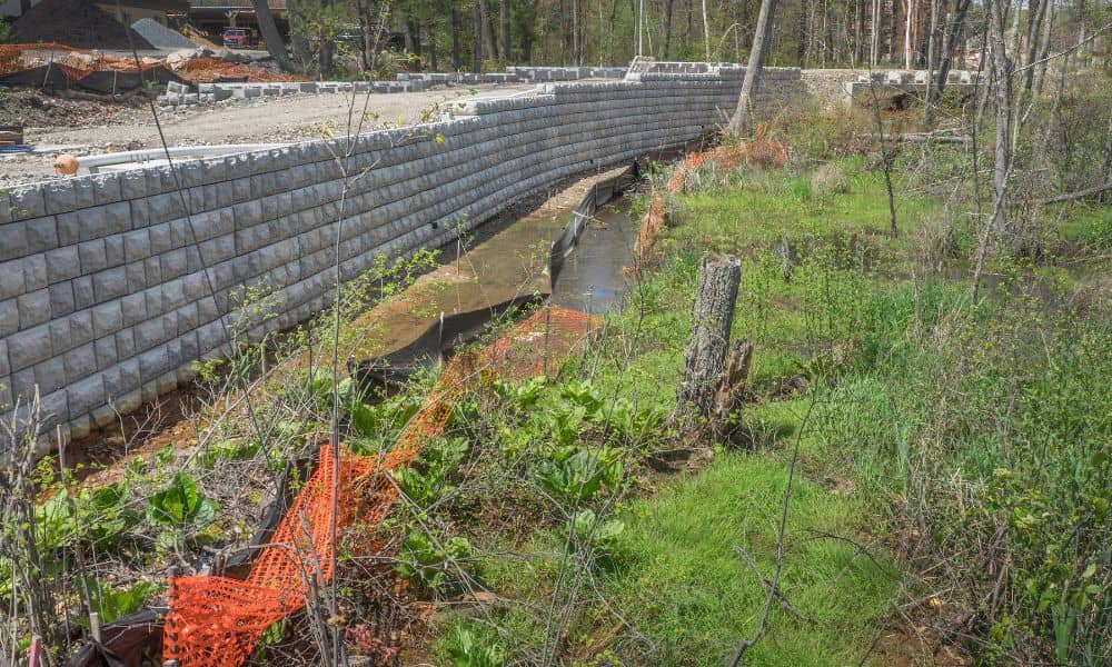 Retaining wall under construction to control soil erosion and manage stormwater runoff in a residential area
