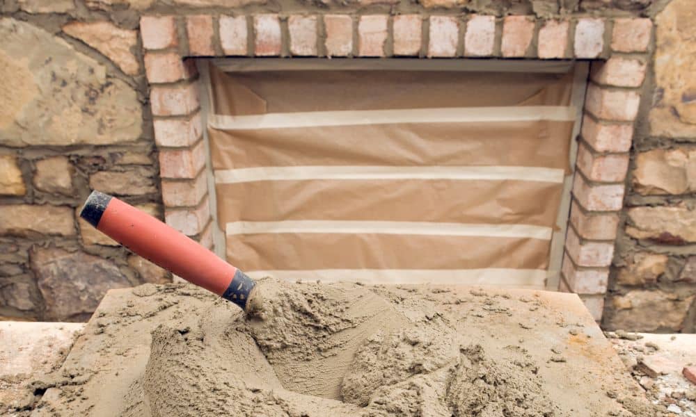 Fresh mortar mix with a trowel on a work surface for a brick hearth repair project
