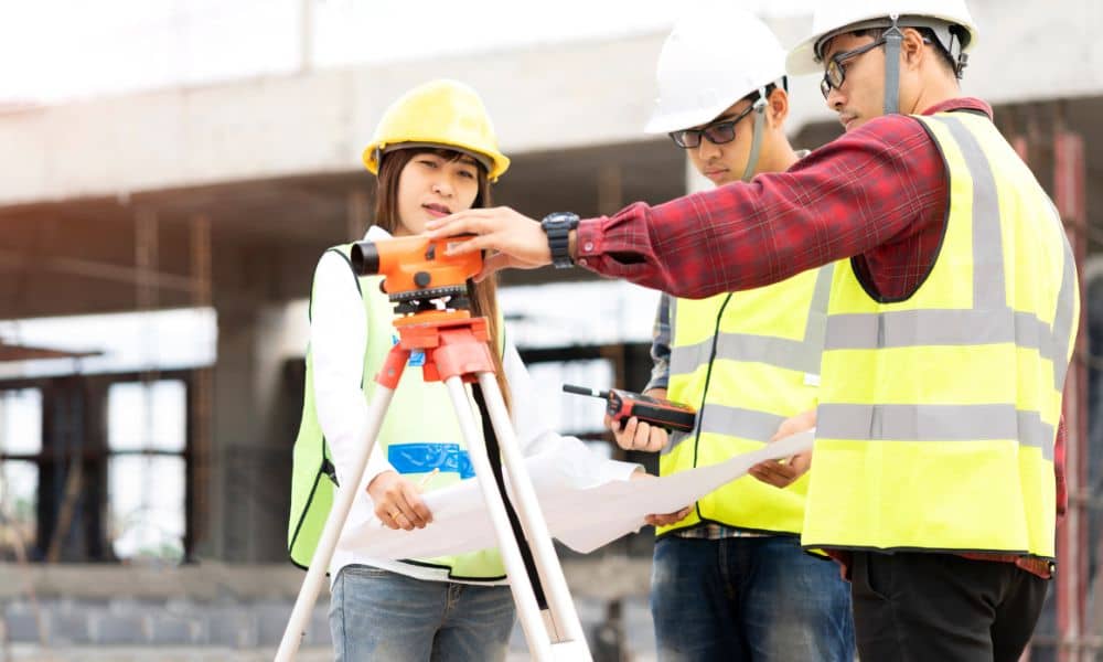 Land surveyors inspecting construction site with bridge project in background for ALTA Land Title Survey accuracy