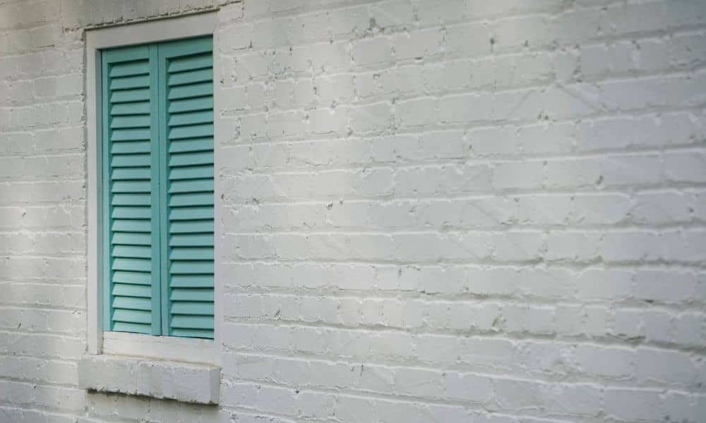 Close up of painted brick exterior with turquoise shutters