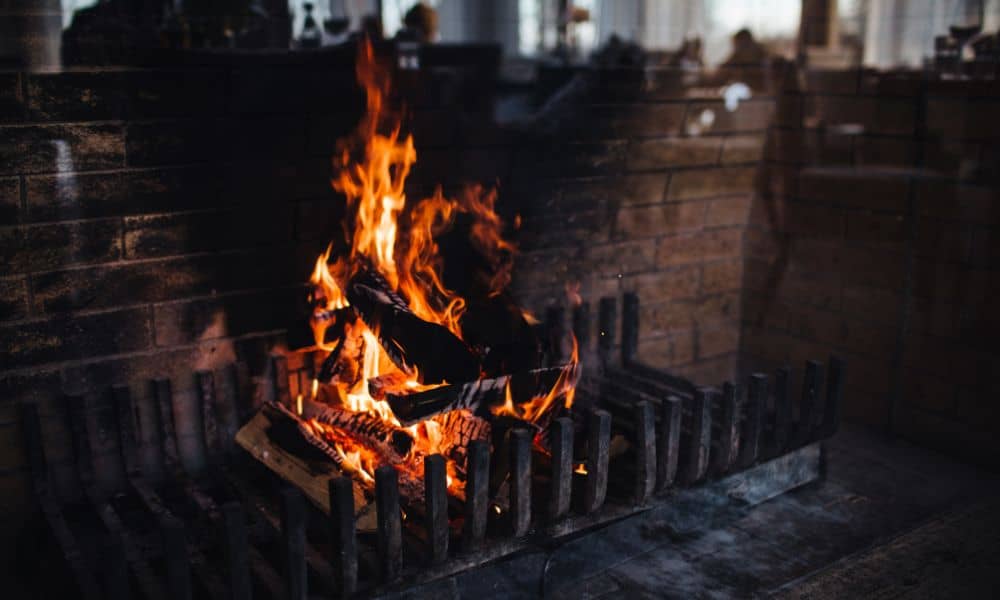 A brick fireplace with active flames and darkened soot marks, showing early signs that may require professional fireplace repair
