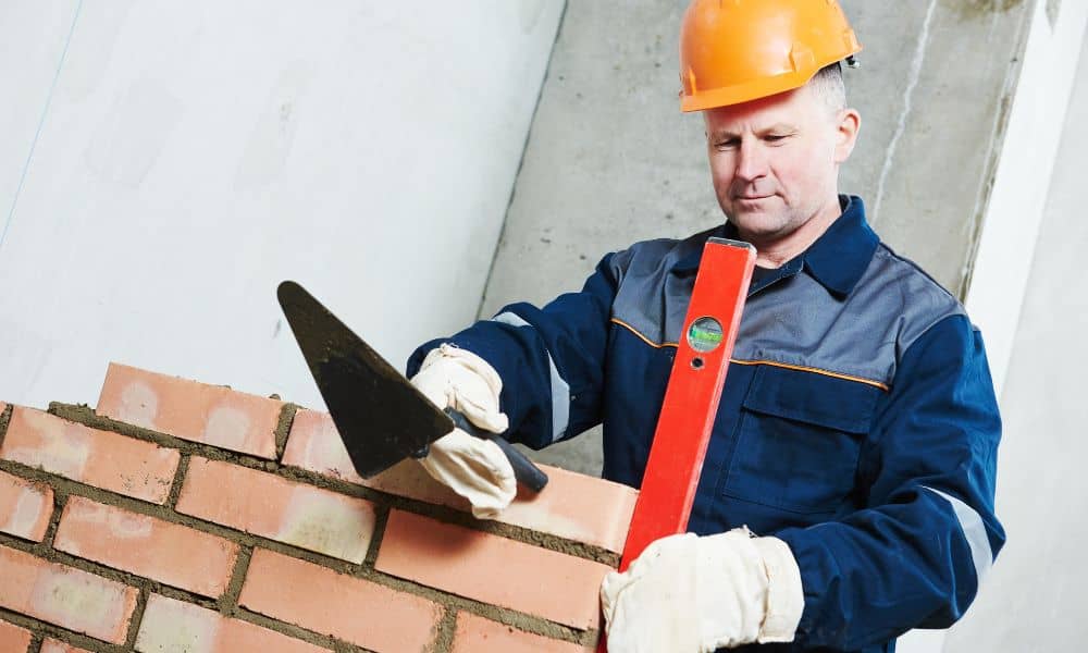 Brick masonry contractor using a level while working on a wall at an active construction site
